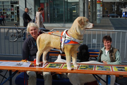 Dieses Bild zeigt den Infostand zum Thema Blindenfuehrhunde - von links nach rechts im Bild Solveig Burauen, ein lebensgro�er  Labrador aus Kunststoff in Arbeitskleidung und Ausbilderin Ute Luhmann